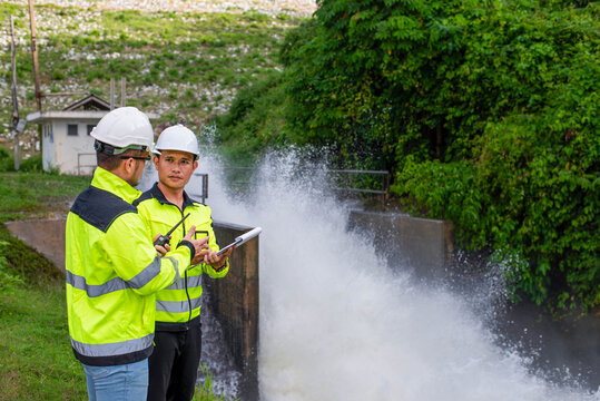 Expert dam engineers are working together to inspect the operation of a large dam's water release system to ensure it is still operating according to standards.