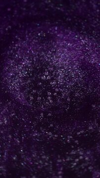 Vertical video. Purple vortex. Spiral paint. Defocused thick dark lilac stream liquid potion mixed with shiny sparkles. Violet caramel boils with bubbles texture.