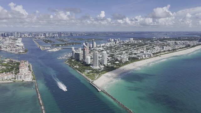 Aerial view of South Pointe Beach, Fisher Island, and Downtown Miami skyline under blue sky. c.