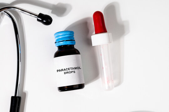 Essential medical items including a bottle of paracetamol drops and a stethoscope arranged on a doctor's desk, ideal for visuals related to treatment, consultation, or child healthcare.