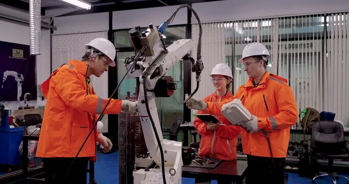 Male technician operating industrial robotic arm with female trainee during automation training session in manufacturing lab focusing on industry40 education, welding programming, and machine control