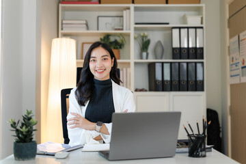 Young asian businesswoman smiling with crossed arms in modern office