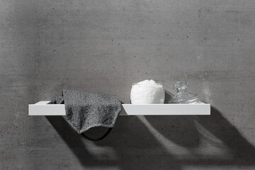 Glass jar with natural sea salt and exfoliating body washcloth on white shelf on gray concrete...