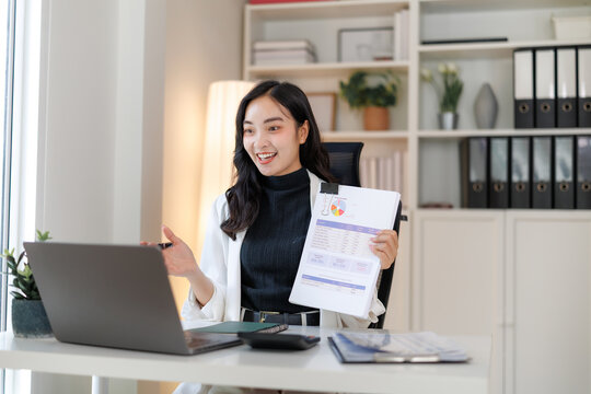 Asian businesswoman showing charts and graphs on video call in office