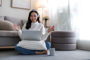 Young woman wearing headphones making video call with laptop at home