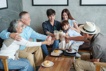 group of the generations family clinking coffee cups together at cafe and bakery