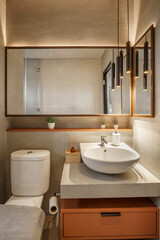 Luxurious modern bathroom with warm ambient lighting. Features a large mirror, vessel sink on a concrete vanity, and stylish pendant lights.