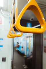 Close-up of yellow hand straps inside a modern train carriage, designed for standing passengers, showcasing urban public transportation and safety in mass transit systems