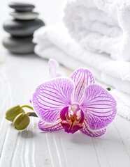 A vibrant purple flower delicately rests atop a stack of soft, fluffy white towels, creating a serene and inviting spa-like atmosphere.