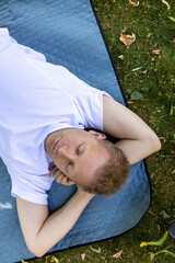 man sleeping on blue quilted blanket in the grass