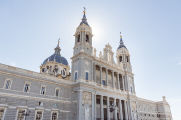 Obraz premium Almudena Cathedral In Madrid With Sun Flare Behind Towers On Clear Blue Day