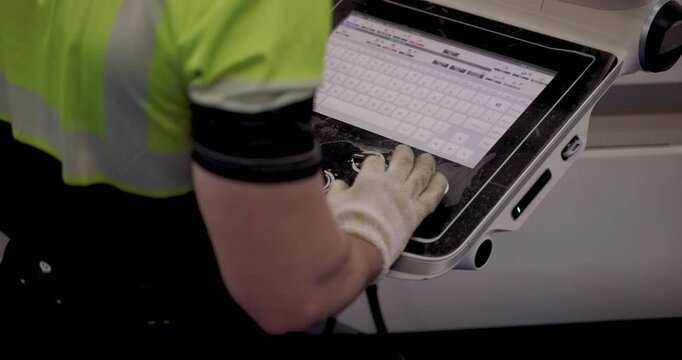 Male technician operating industrial touch interface on CNC controller during slowmotion factory automation training for input validation, production setup, and data confirmation in industry40 system