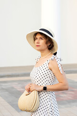 Close-up portrait of a woman in a wide-brimmed straw hat with black ribbon and polka dot dress,...