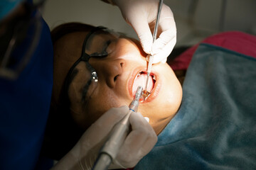 Dentist using dental drill and other tools while examining patient's teeth