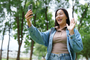 Young woman making video call and waving in park
