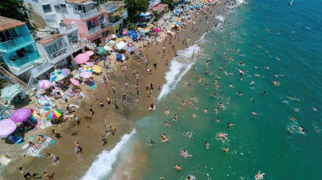 Crowded beach with colorful umbrellas and people enjoying sunny day by ocean water