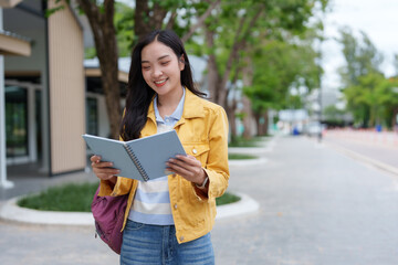 Smiling university student reading a book outdoors on campus