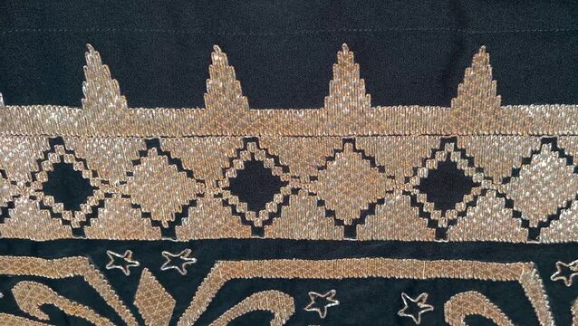 a traditional Indonesian fabric called kain tapis from Lampung, featuring floral and geometric motifs with gold thread on a black background, symbolizing cultural elegance and heritage