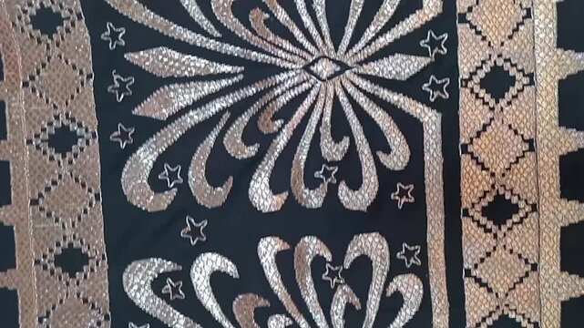 a traditional Indonesian fabric called kain tapis from Lampung, featuring floral and geometric motifs with gold thread on a black background, symbolizing cultural elegance and heritage