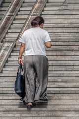 A woman walks up the stairs of an above-ground pedestrian crossing on a summer day