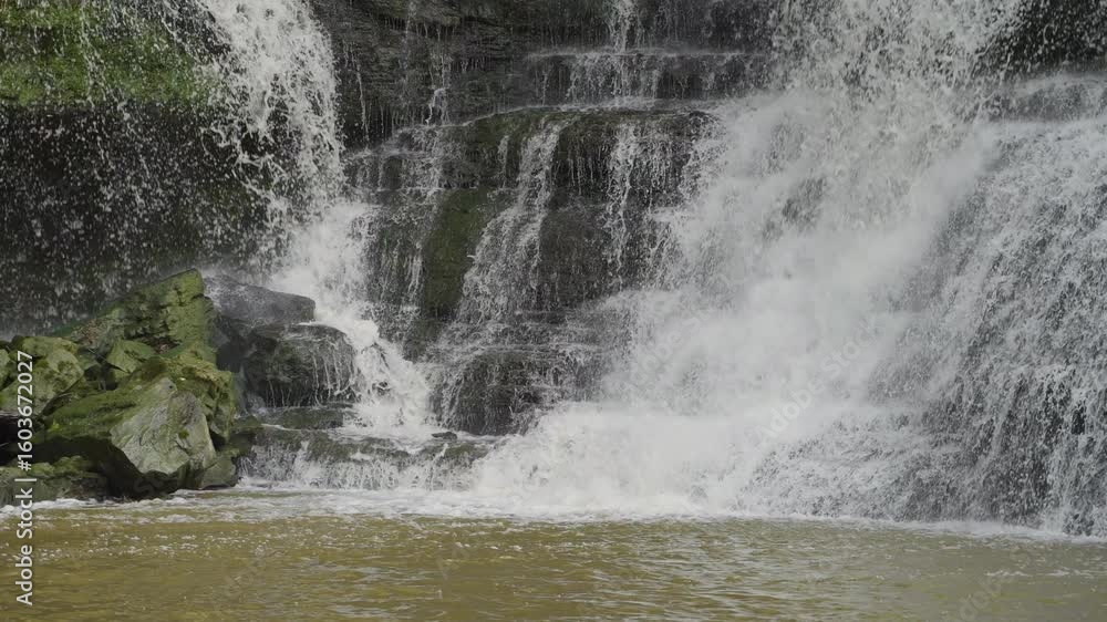 Poster slow motion of powerful waterfall crashing over rocks creating dynamic water textures