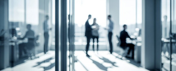 People working in a modern office space with large windows and bright light.