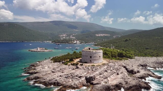 Low aerial approaches Arza fortress on rocky headland, Montenegro