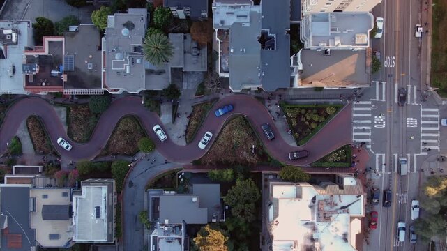 Aerial view of Lombard Street, known for its steep, one-block section with eight hairpin turns, cars navigate the curves, tourists walk, San Francisco, USA.