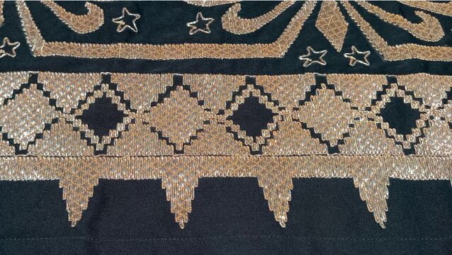 a traditional Indonesian fabric called kain tapis from Lampung, featuring floral and geometric motifs with gold thread on a black background, symbolizing cultural elegance and heritage
