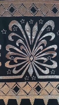 a traditional Indonesian fabric called kain tapis from Lampung, featuring floral and geometric motifs with gold thread on a black background, symbolizing cultural elegance and heritage