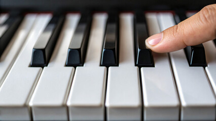 Fototapeta premium Close-Up of a Finger Pressing a Piano Key on a Musical Instrument Keyboard