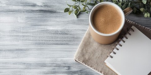 A cup of coffee sits on a table next to a notebook