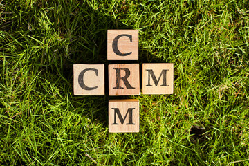  wooden blocks arranged to spell "CRM" with a soft, blurred green background. This image represents Customer Relationship Management, a crucial concept in modern business and finance