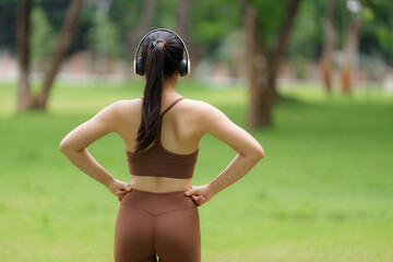 Sporty woman listening to music in the park after exercising