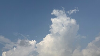 Bright cumulus cloud is drifting slowly across the beautiful light blue morning sky