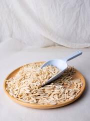 White Almond Stick set on wooden board with versatile scoop and white background.