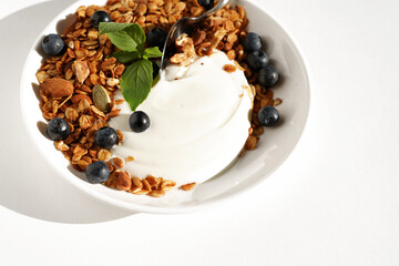 Natural Greek Yogurt with Homemade Granola with Nuts and Seeds, Served with Fresh Forest Blueberries. Eating Breakfast.	