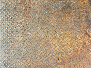 A detailed close-up of heavily rusted diamond plate metal, showcasing a rich, textured surface with varying shades of brown, orange, and grey. Perfect as an industrial or grunge background.