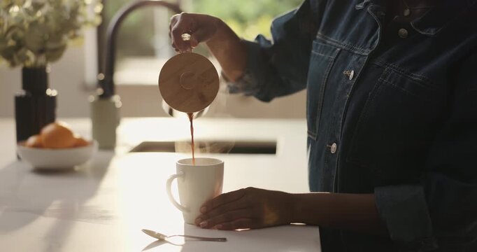 Pouring, coffee and hands with cup, kitchen and preparing breakfast to start day or morning routine. Hot, beverage or person with caffeine on counter in home, liquid or equipment for tea in apartment