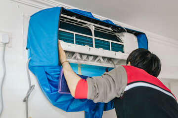 Technician cleaning and maintaining an air conditioning unit