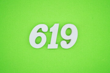 The numbers are made of white painted wood and placed on a green paper background.
