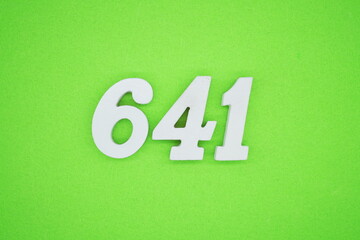 The numbers are made of white painted wood and placed on a green paper background.