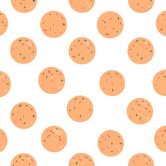 Obraz premium Round orange Indian Laddu sweets, a traditional dessert ball speckled with colorful red and green nut pieces.