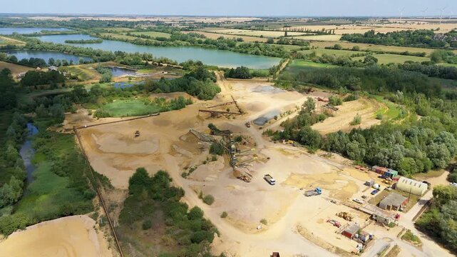 Aerial drone footage of Little Paxton quarry mining operation with heavy plant machinery extracting minerals in England