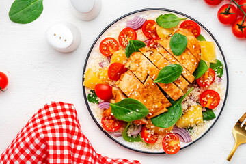 Salad with chicken fillet, couscous, cherry tomatoes, red onion, fresh spinach and orange slices, top view
