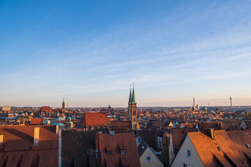 Panoramic view of the rooftops and church spires of Nuremberg's old town at sunset.