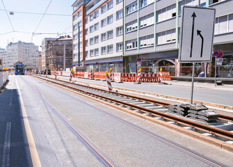 Tramway construction site with visible rails, traffic signs, and surrounding residential buildings.