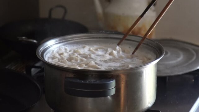 	うどんを茹でる女性