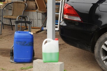 A black car with containers of cleaning fluids parked outside, ready for maintenance.