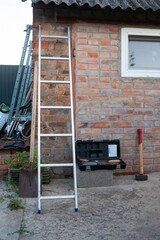 A ladder and tools lean against a brick building, ready for a home improvement project.